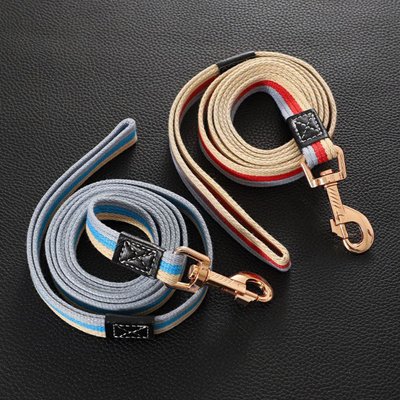 Deux modèles de laisse pour chien en tissu avec mousquetons métalliques posés sur une surface noire