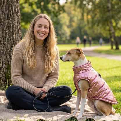 Manteau Chien rose porté par un chien assis près d’une personne au parc