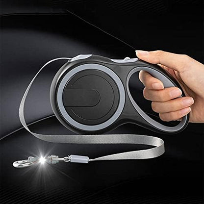 Une main tient la Laisse Rétractable Chien | MaxLeash (Noir), une laisse rétractable noire pour chien avec une lumière LED près du fermoir, disponible en 3m/5m/8m pour les chiens jusqu'à 50kg, sur un fond sombre.