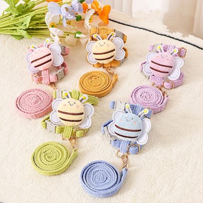 Six Harnais pour Chien | Des laisses rétractables en forme de papillon avec des décorations d'abeilles en peluche de couleur rose pastel, jaune, violet, vert et bleu sont disposées sur une surface claire. Un bouquet de fleurs artificielles se trouve à l'arrière-plan.